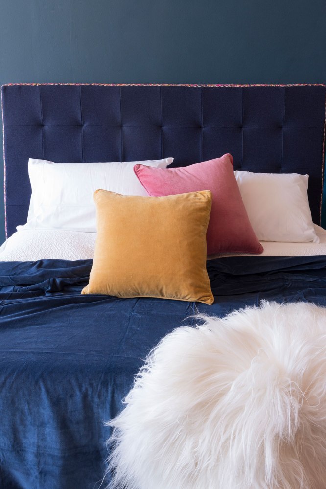Photographie publicitaire d'un lit avec parure de lit et oreillers colorés.